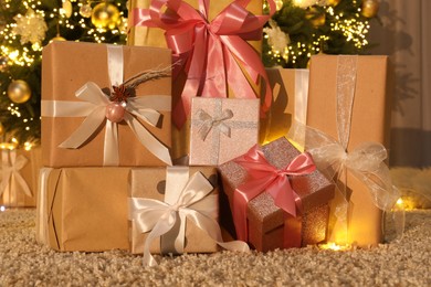 Many gift boxes near decorated Christmas tree at home