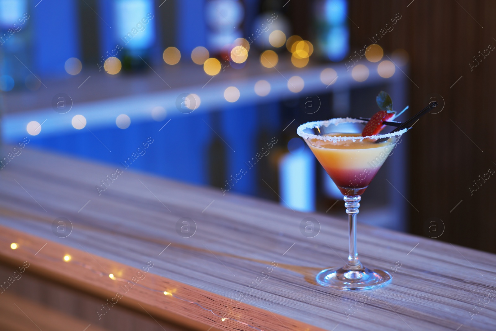 Photo of Delicious strawberry martini cocktail on table in bar, space for text