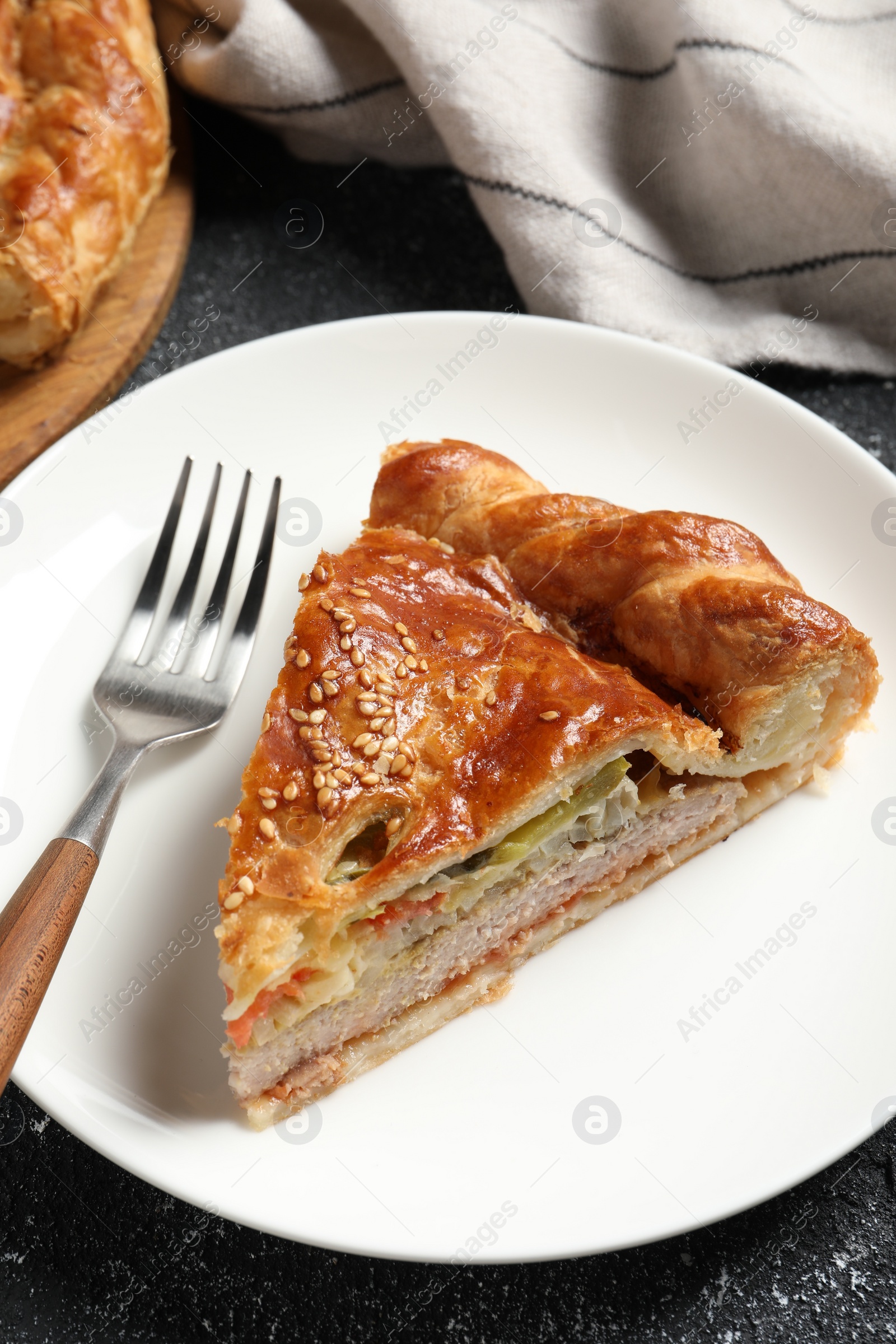 Photo of Piece of tasty homemade pie with filling on black table