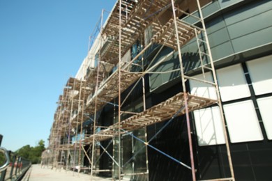 Blurred view of unfinished building with scaffolding against blue sky