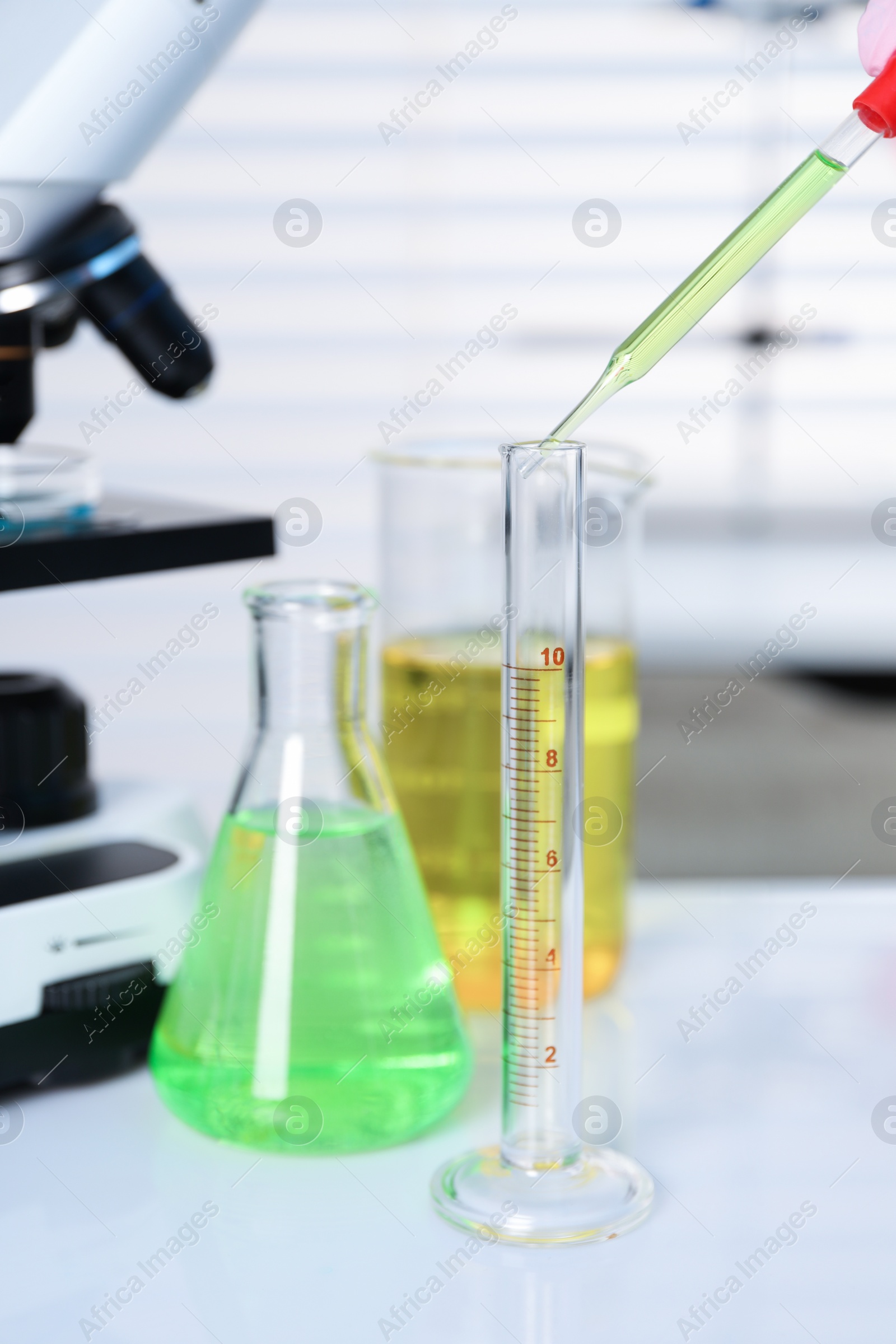 Photo of Laboratory analysis. Dripping liquid into test tube on white table, closeup