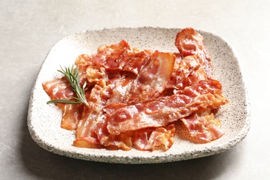 Plate with fried bacon on grey background