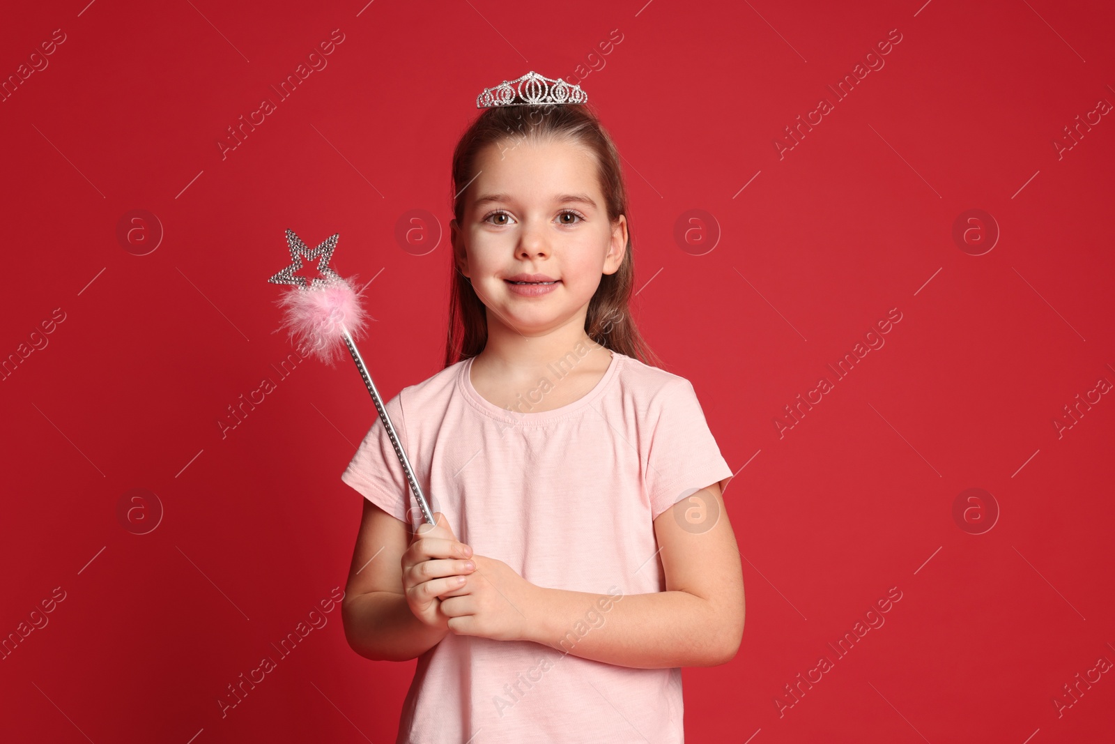 Photo of Cute girl in diadem with magic wand on red background. Little princess