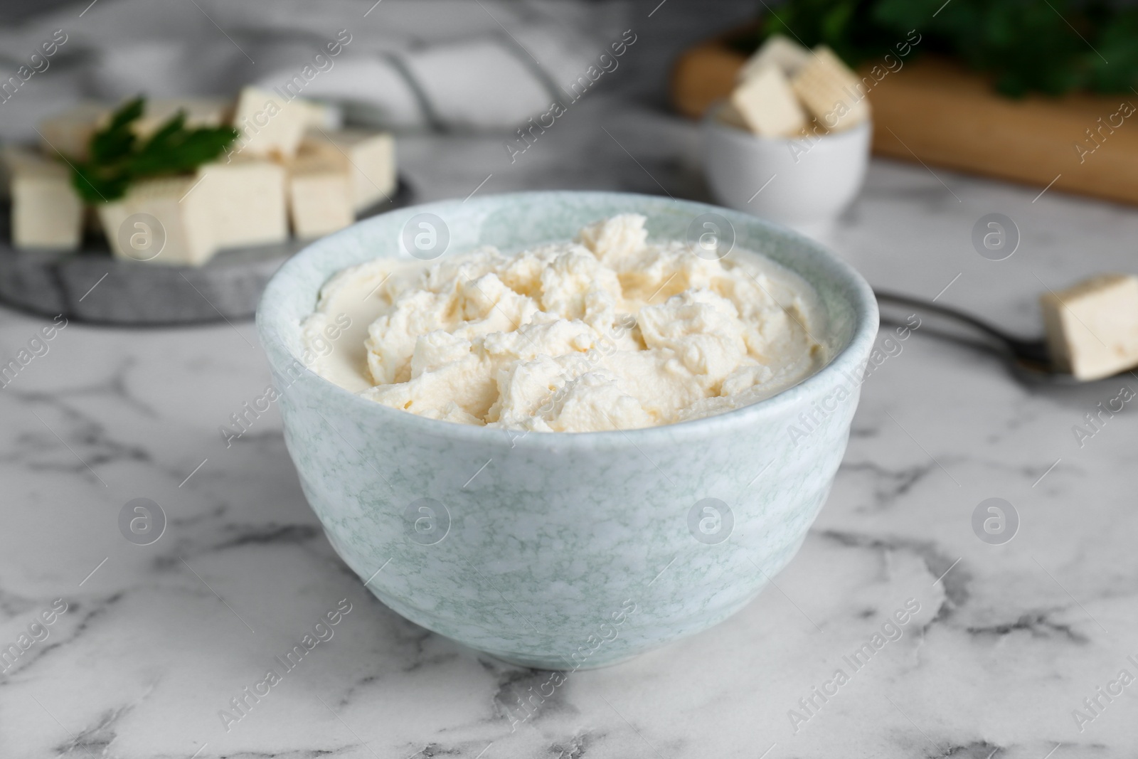 Photo of Delicious tofu cream cheese in bowl on white marble table, closeup