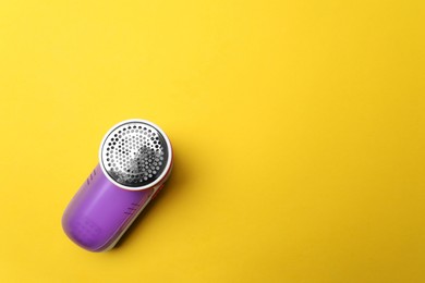 Modern fabric shaver on yellow background, top view. Space for text