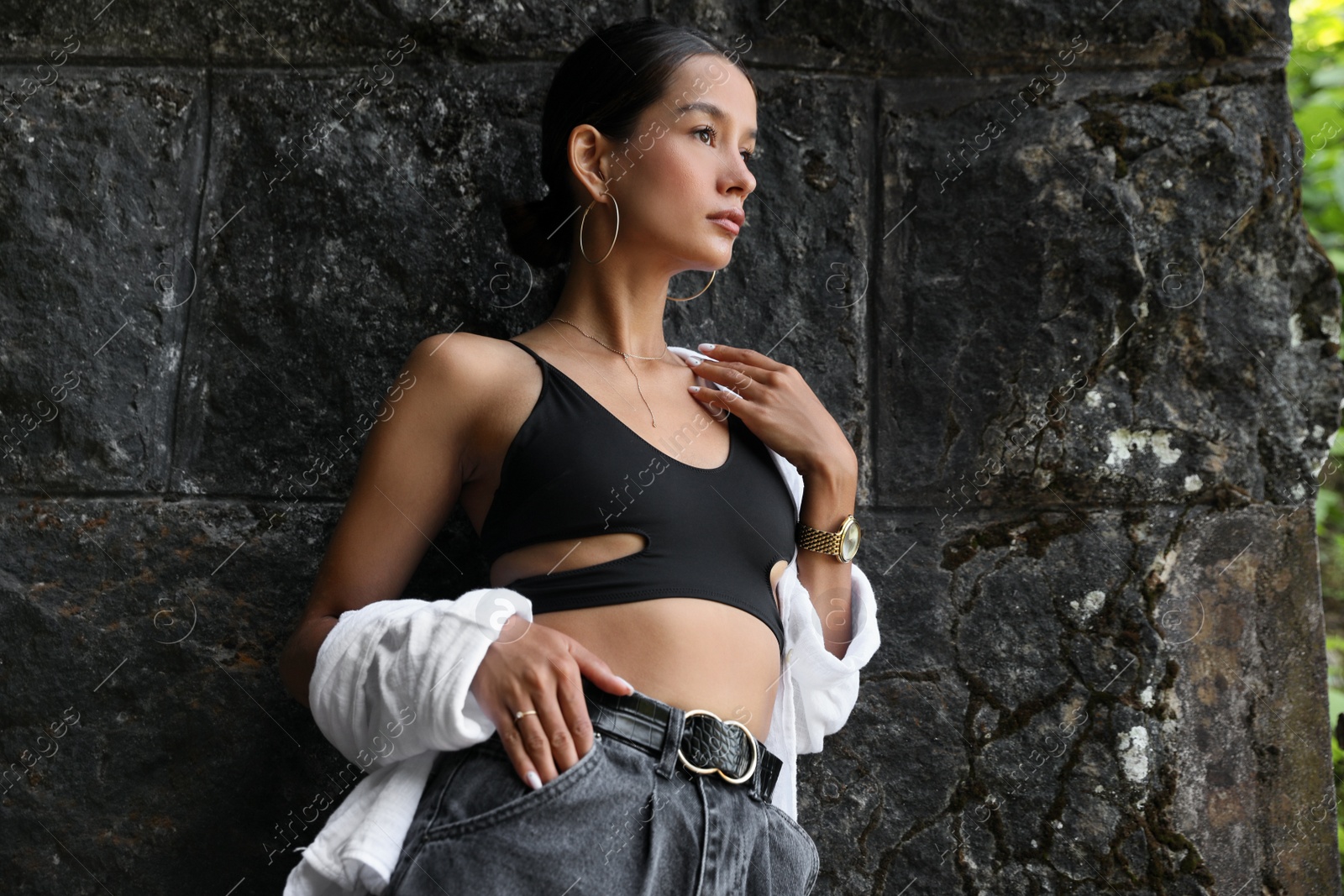 Photo of Beautiful young woman near stone wall outdoors