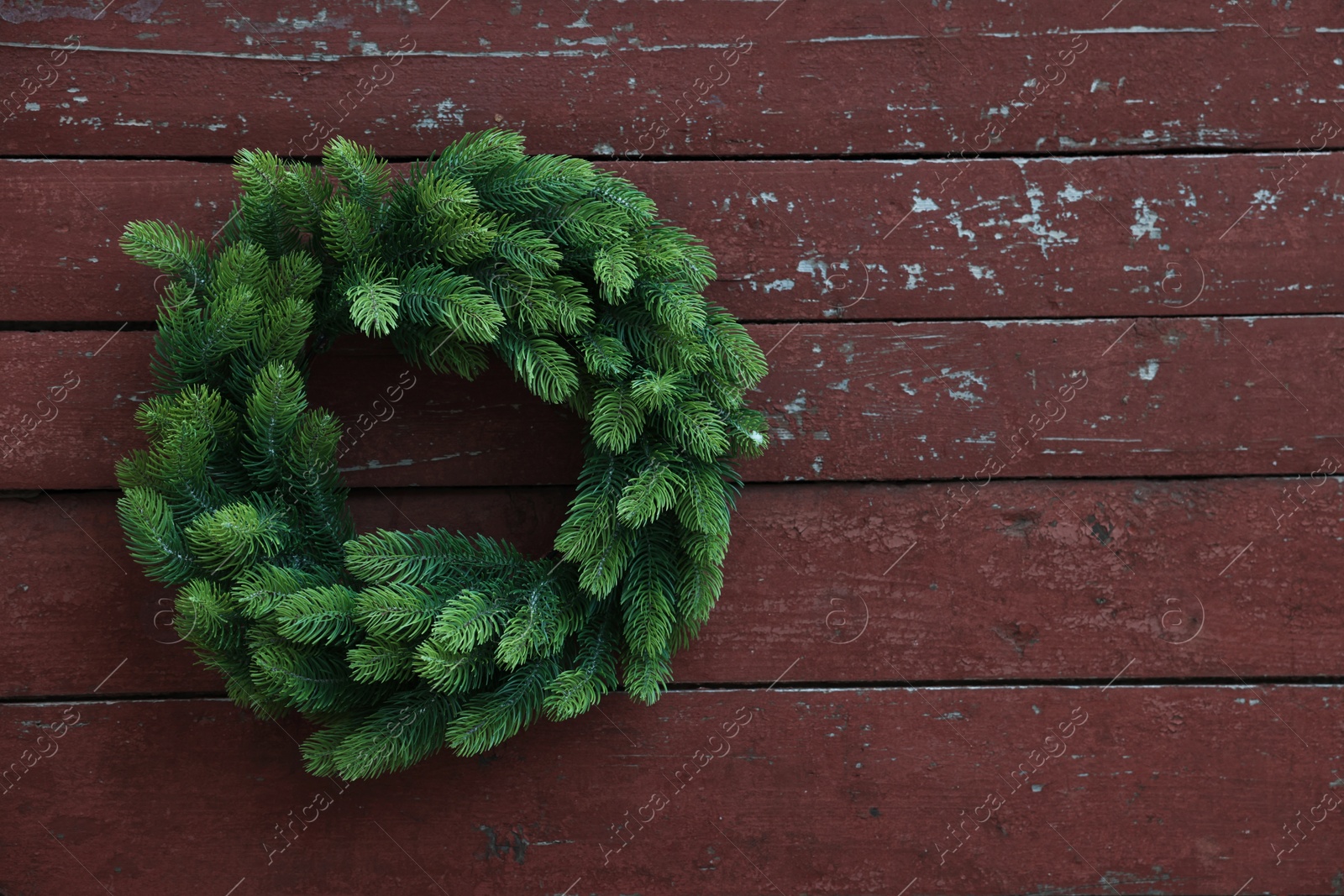 Photo of Beautiful Christmas wreath hanging on brown wooden wall, space for text