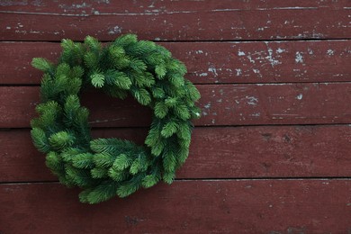 Beautiful Christmas wreath hanging on brown wooden wall, space for text