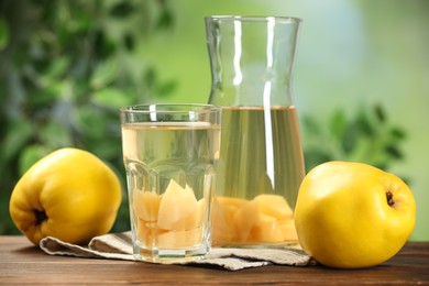 Delicious quince drink and fresh fruits on wooden table against blurred background