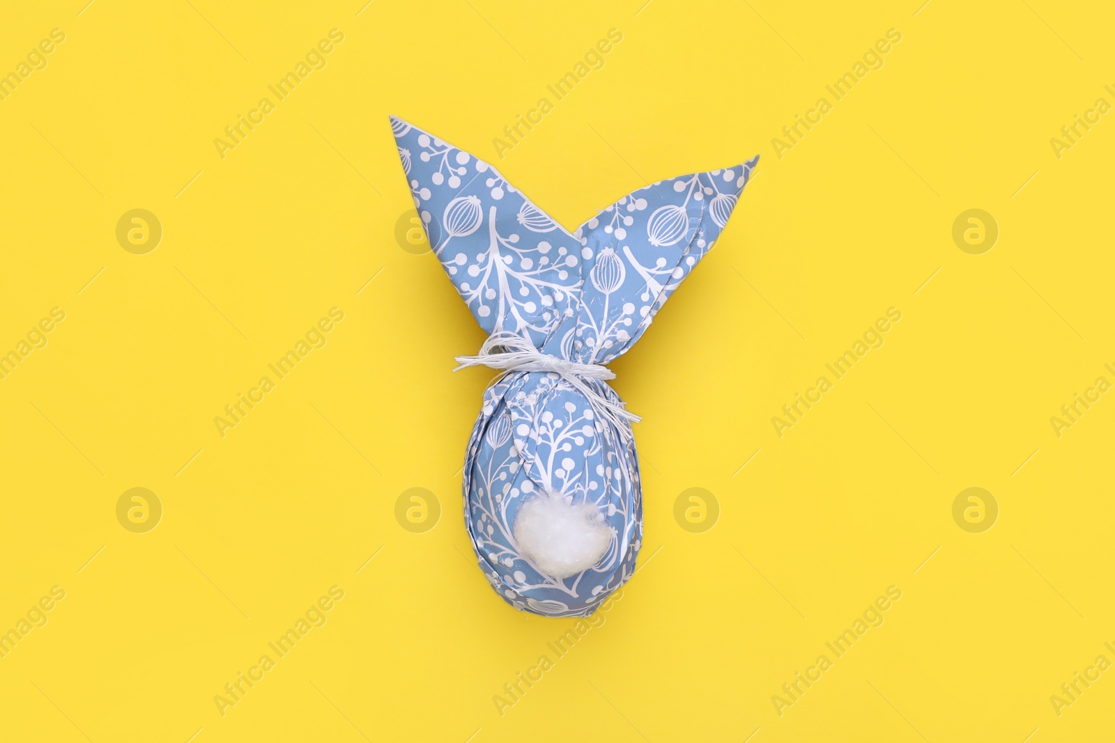 Photo of Easter bunny made of paper with pattern and egg on yellow background, top view