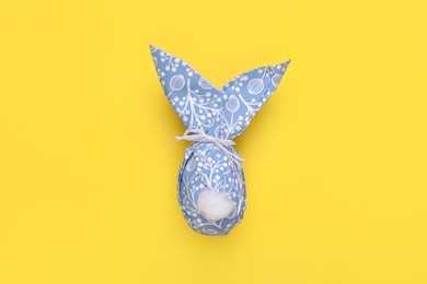 Photo of Easter bunny made of paper with pattern and egg on yellow background, top view