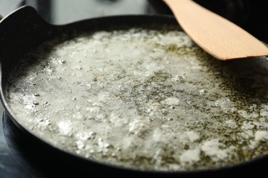 Photo of Melted butter in frying pan and wooden spatula on table, closeup