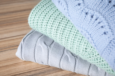 Image of Stack of folded warm sweaters on wooden table, closeup