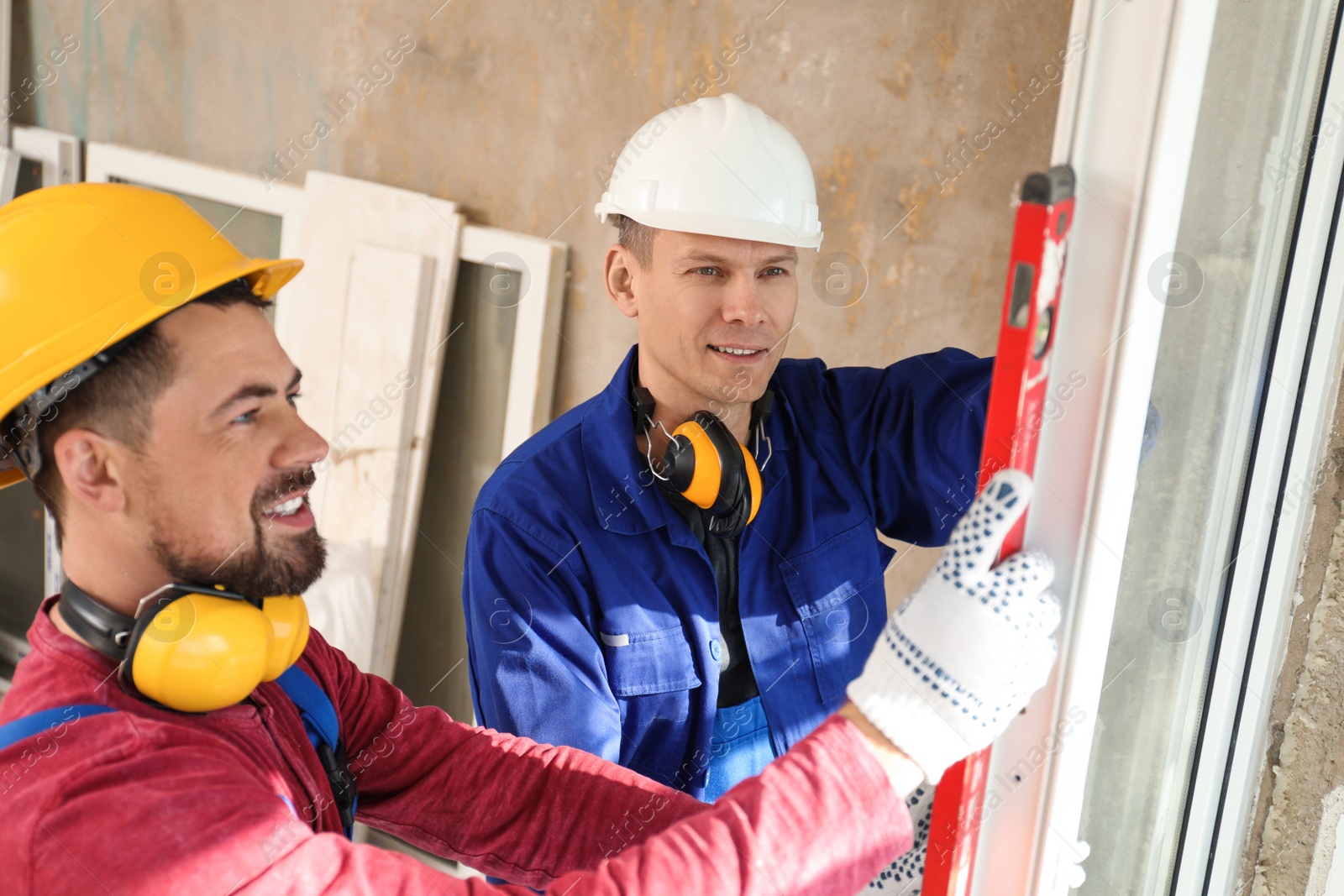 Photo of Workers using bubble level for installing window indoors