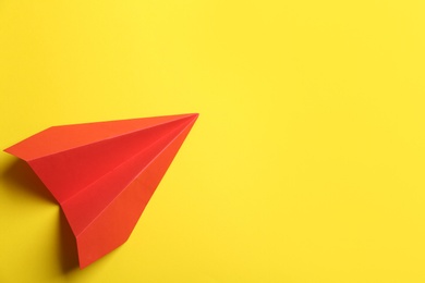 Photo of Red paper plane on yellow background, top view. Space for text