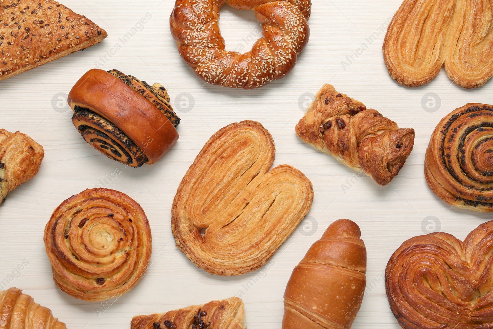 Photo of Different tasty freshly baked pastries on white wooden table, flat lay