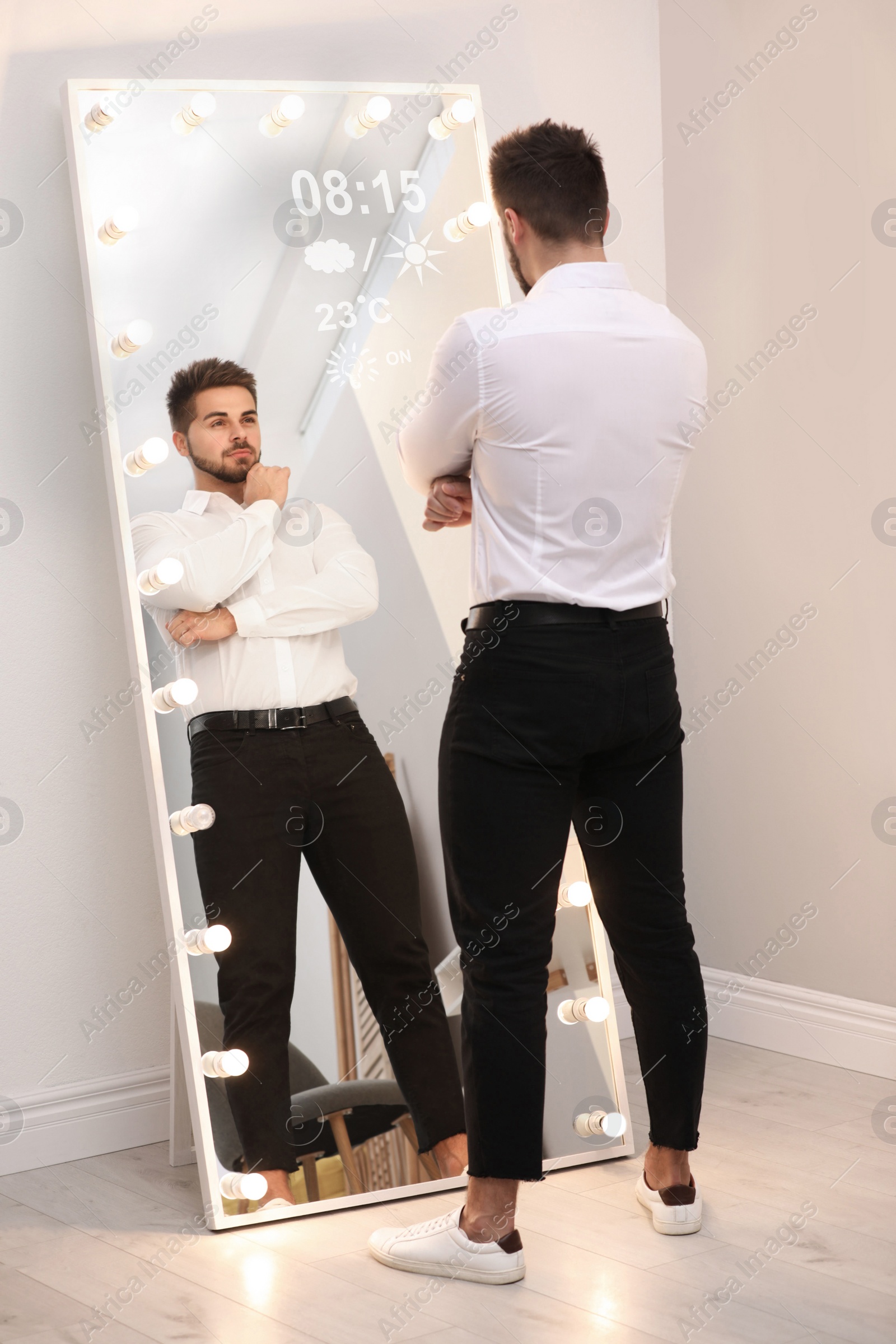 Image of Young man looking at himself in smart mirror at home