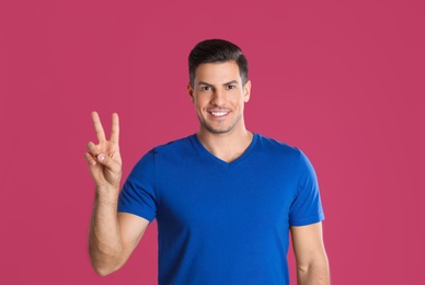 Photo of Man showing number two with his hand on pink background