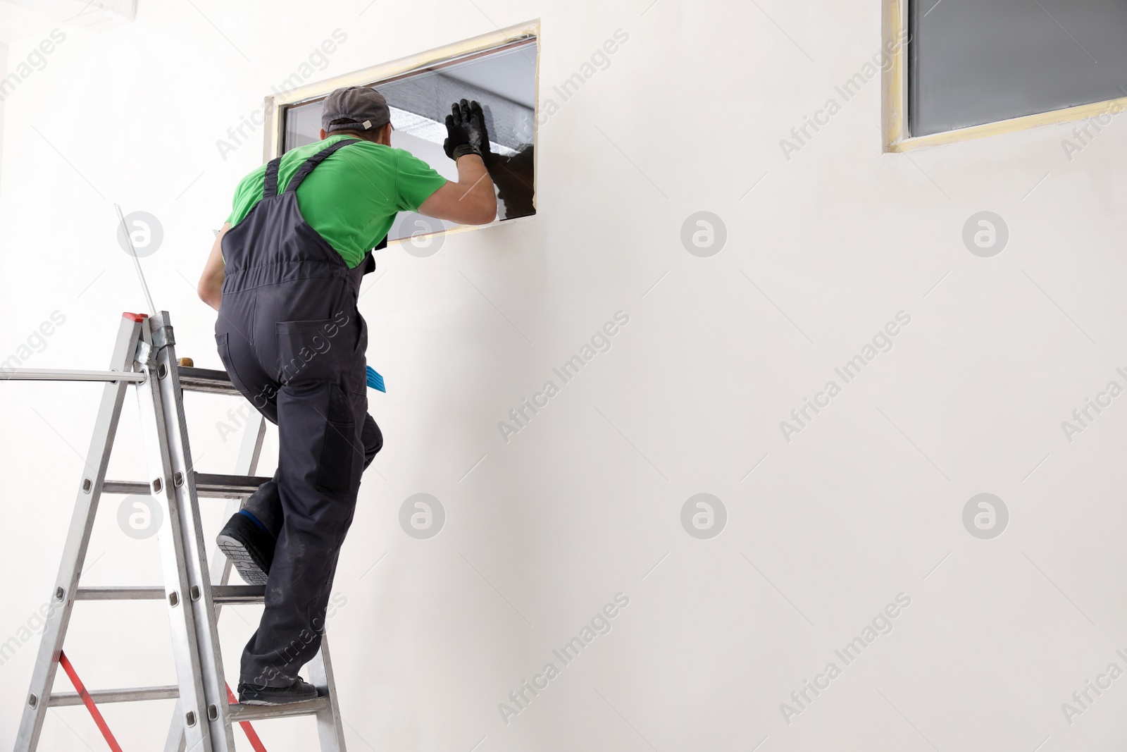 Photo of Worker in uniform installing double glazing window indoors