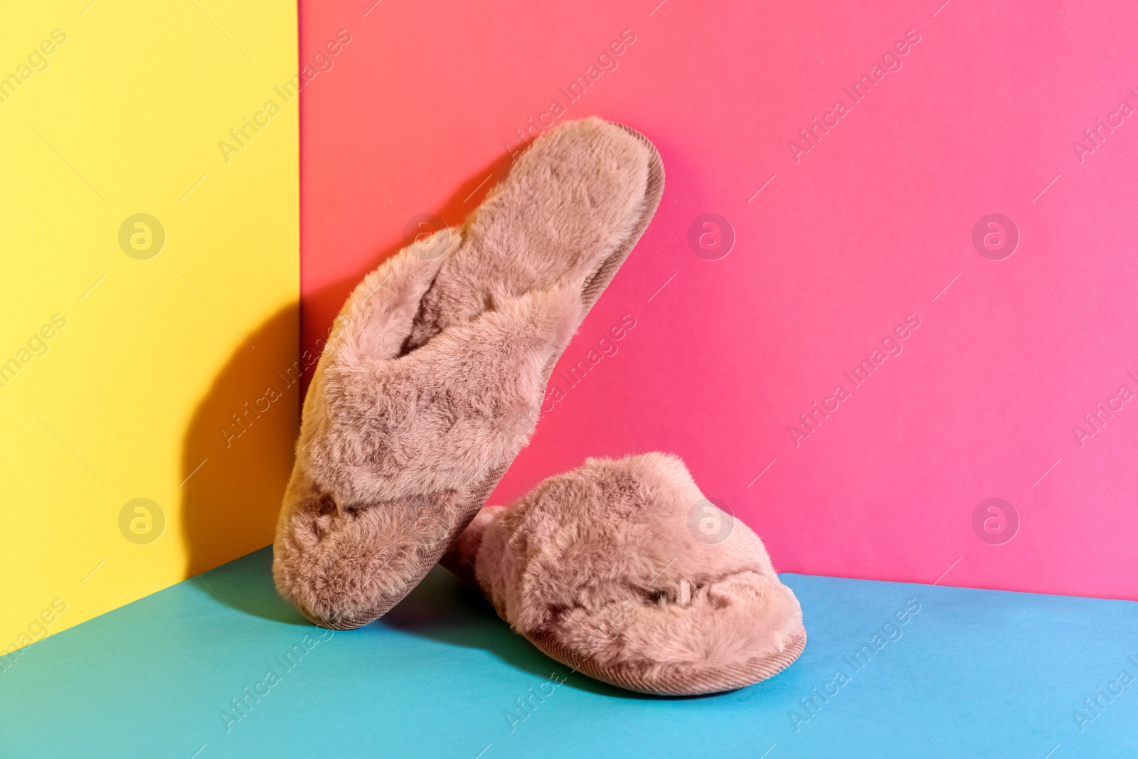 Photo of Pair of soft slippers on color background