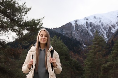 Happy woman with backpack in beautiful mountains. Space for text