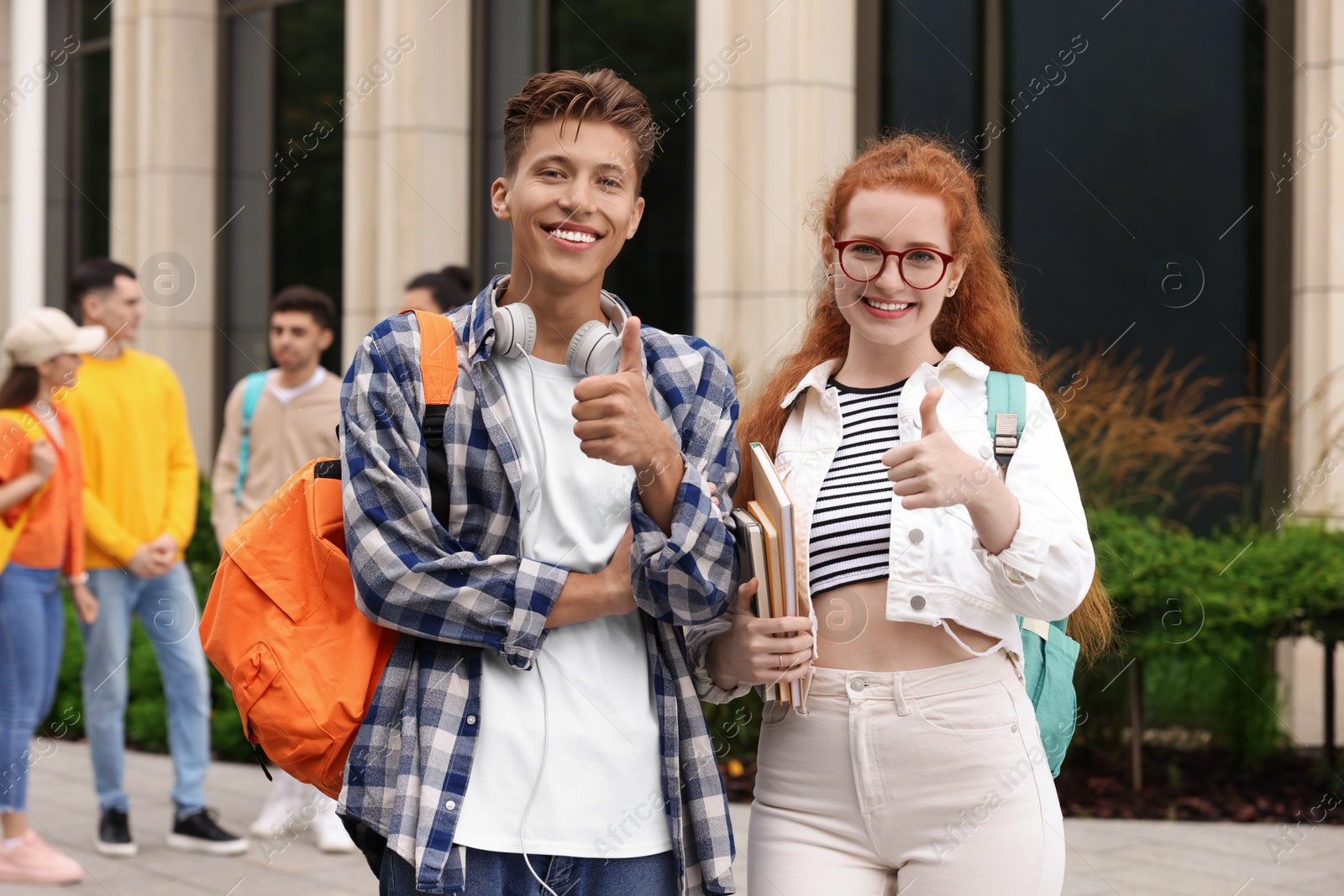 Photo of Happy young students showing thumbs up outdoors