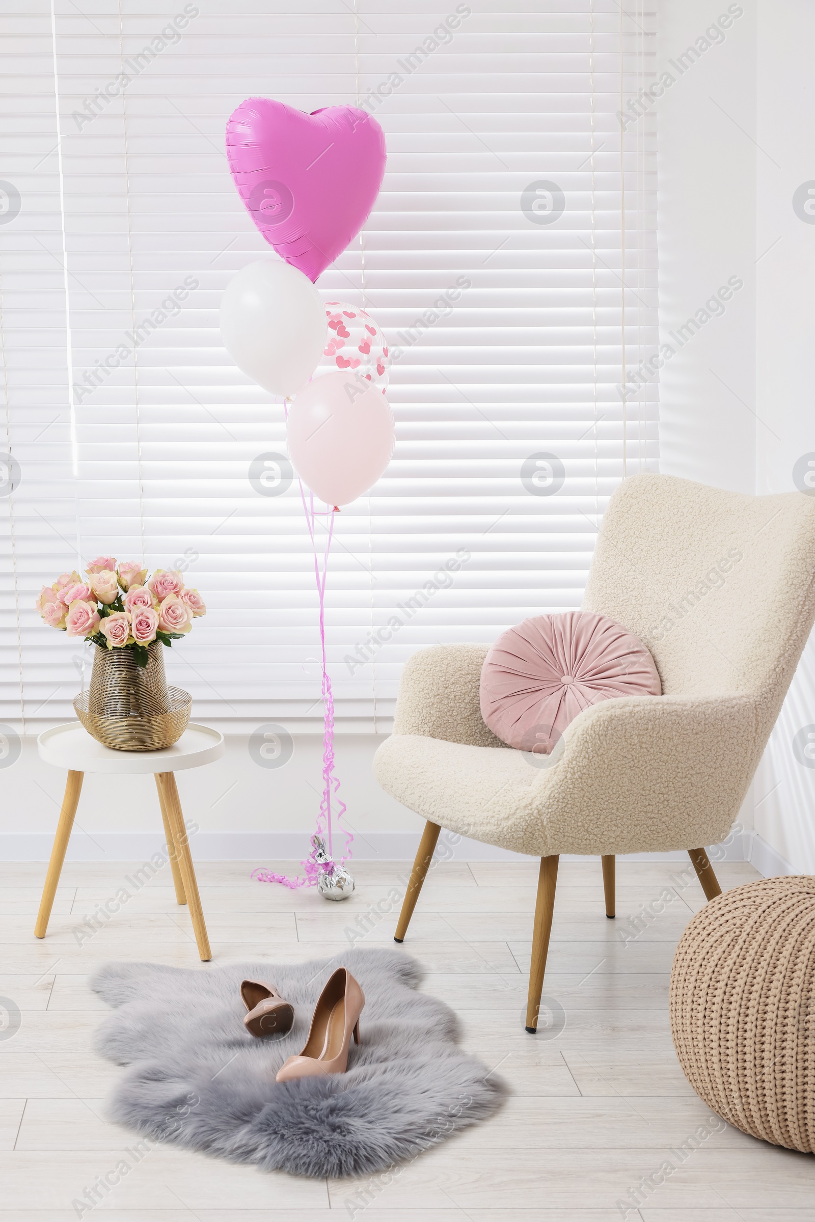 Photo of Beautiful roses on coffee table, comfortable armchair and air balloons in cozy room. Happy birthday