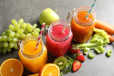 Mason jars with different juices and fresh ingredients on table