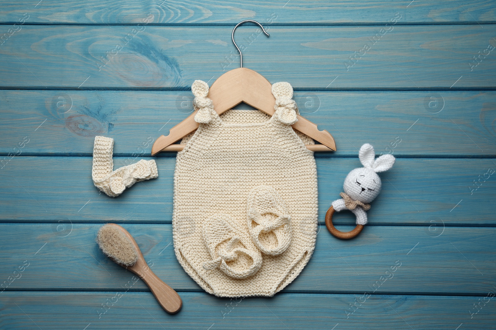 Photo of Flat lay composition with cute baby knitwear for photoshoot on light blue wooden background