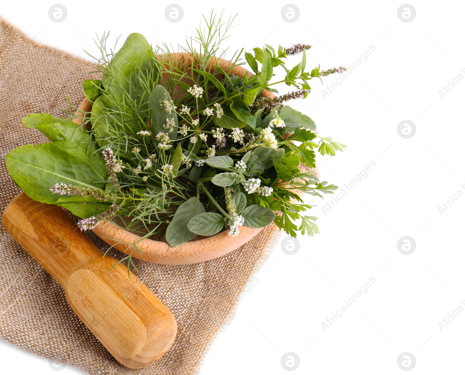 Photo of Wooden mortar, pestle and different herbs on cloth against white background