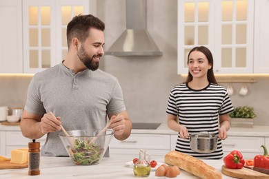 Lovely young couple cooking together in kitchen