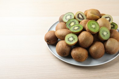 Fresh ripe kiwis on light wooden table, space for text