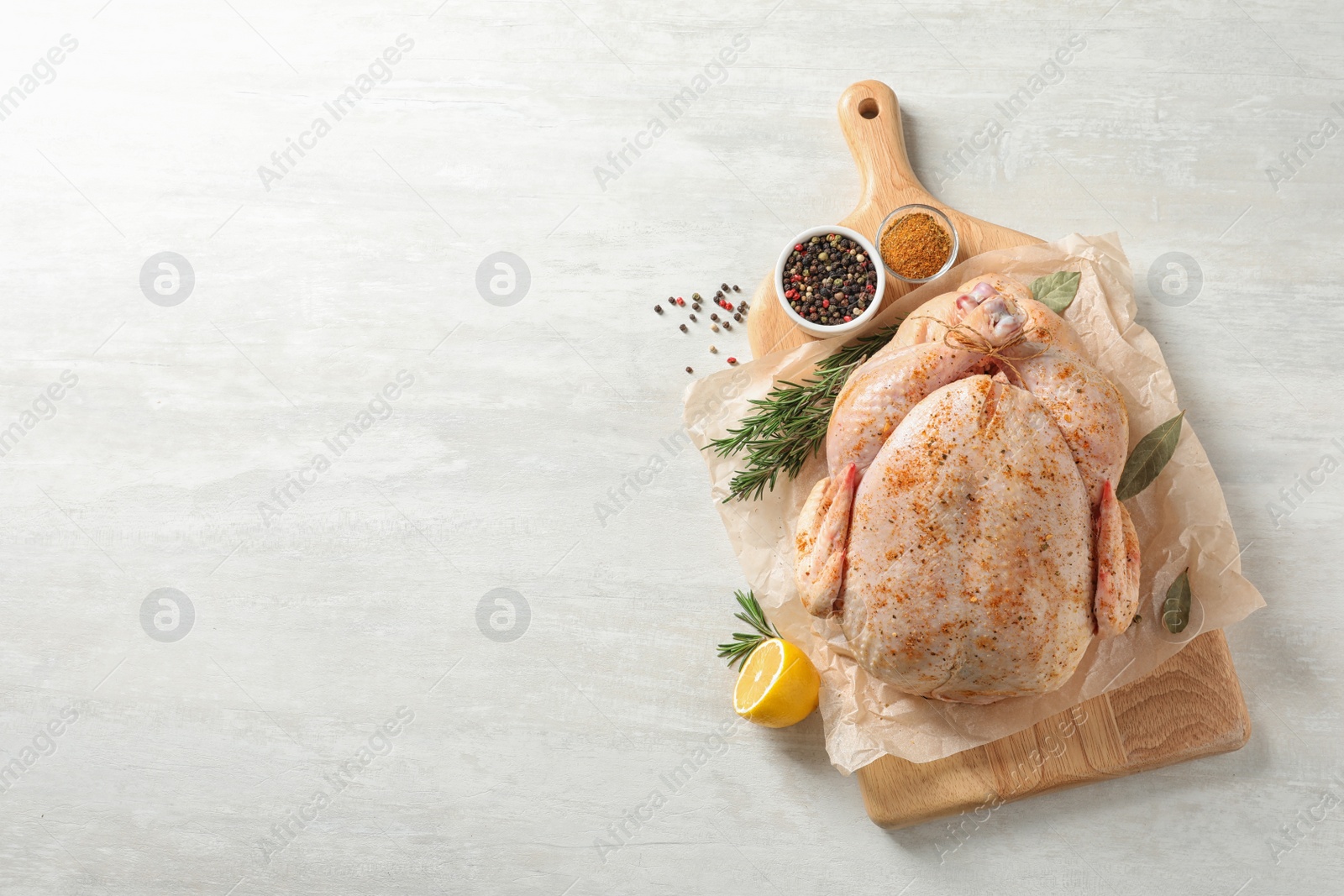 Photo of Board with raw spiced turkey and ingredients on light background, top view. Space for text