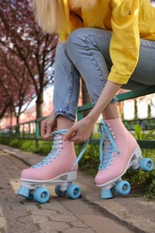 Photo of Young woman putting on roller skates outdoors, closeup