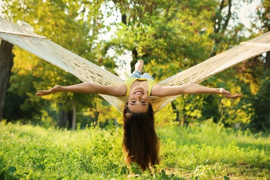 Photo of Young woman resting in comfortable hammock at green garden