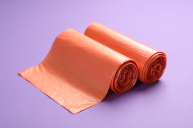 Photo of Rolls of orange garbage bags on violet background