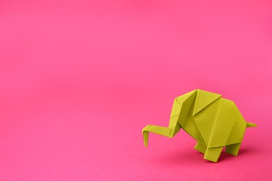 Photo of Yellow paper elephant on pink background, space for text. Origami art