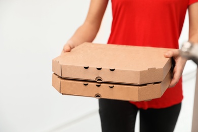 Photo of Female courier with pizza boxes indoors, closeup. Food delivery service