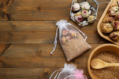 Scented sachet with dried roses and sea salt on wooden table, flat lay. Space for text