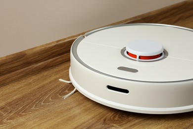 Photo of Robotic vacuum cleaner on wooden floor indoors, closeup