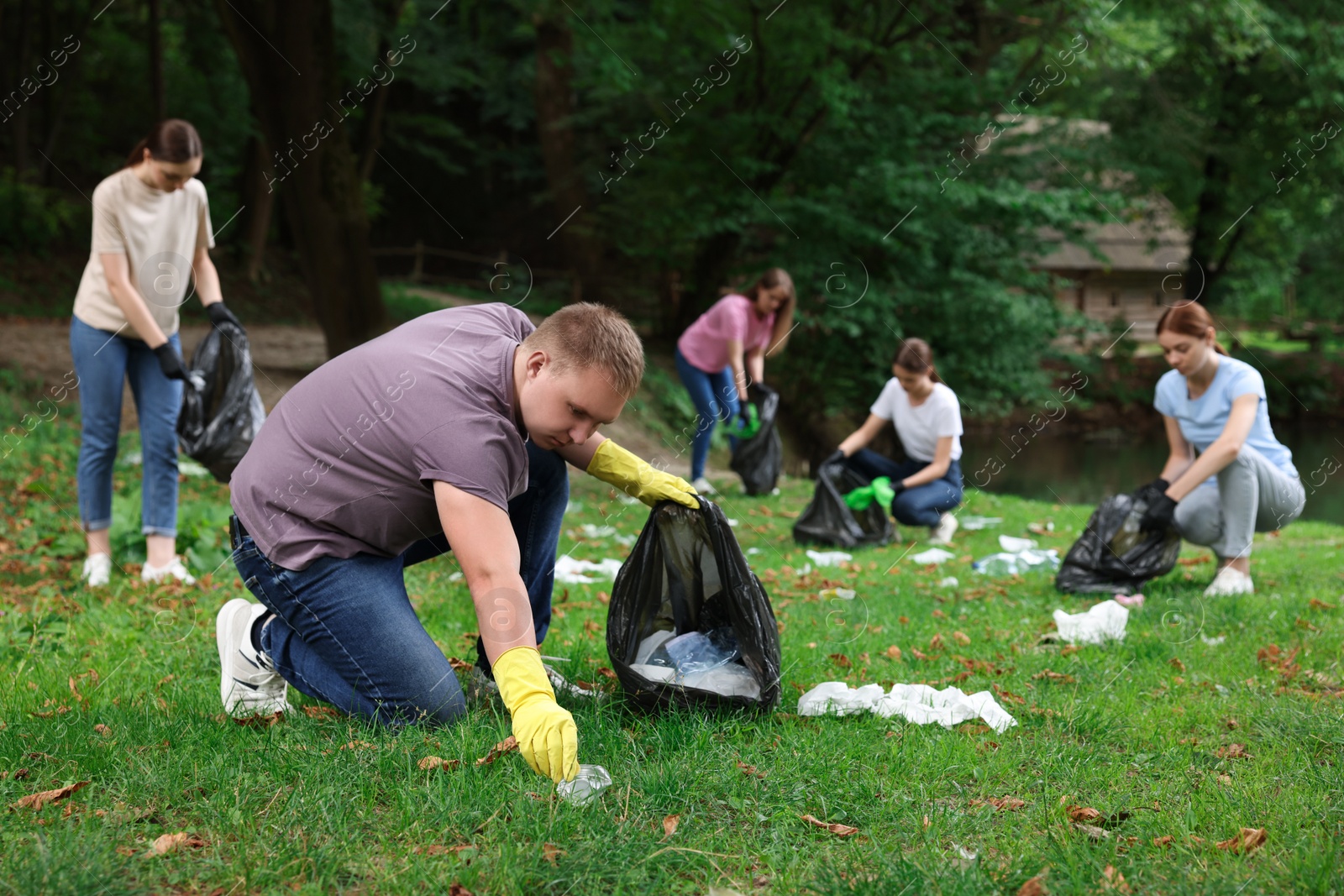 Photo of Group of people with plastic bags collecting garbage in park