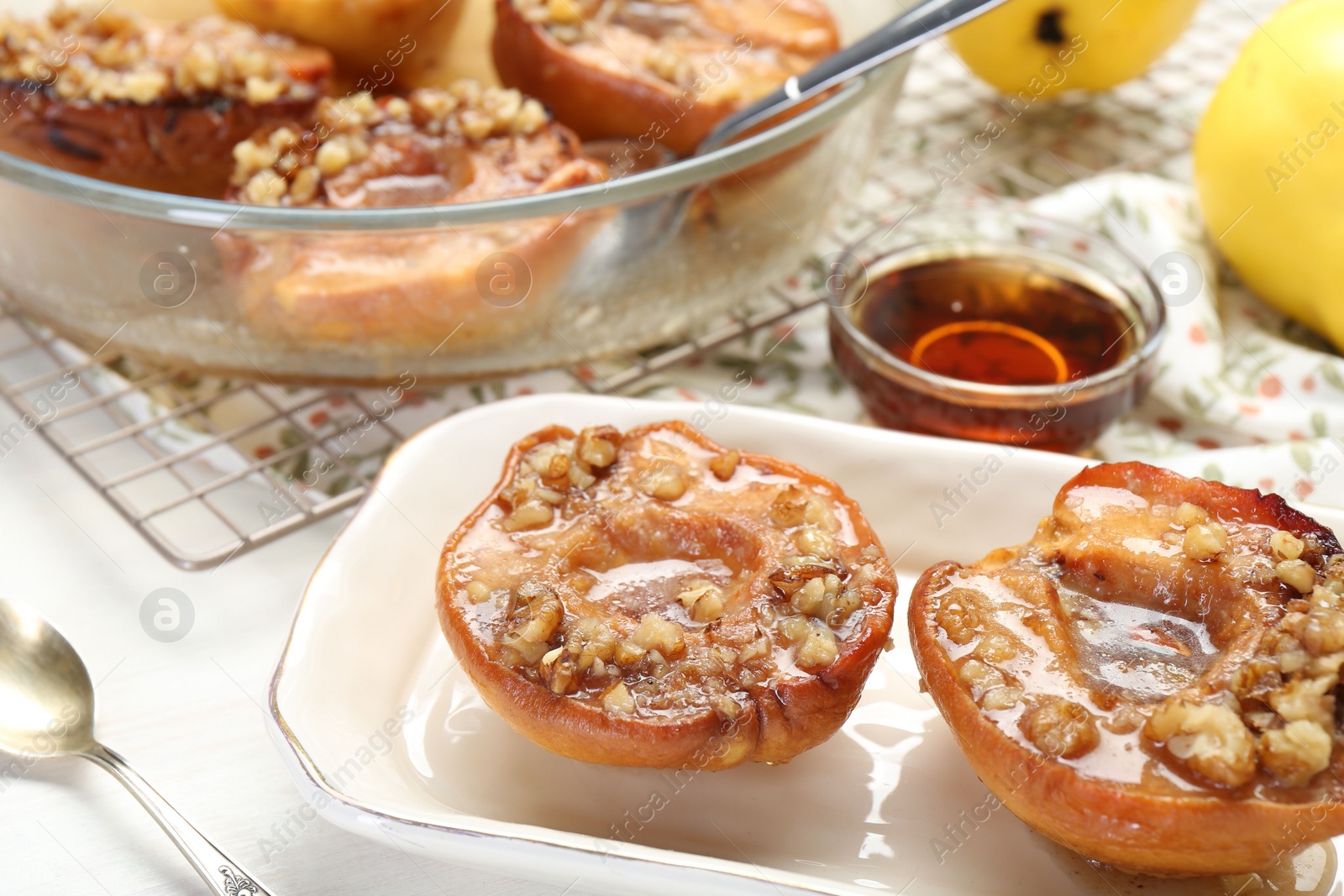 Photo of Delicious quinces baked with honey and walnuts on white table