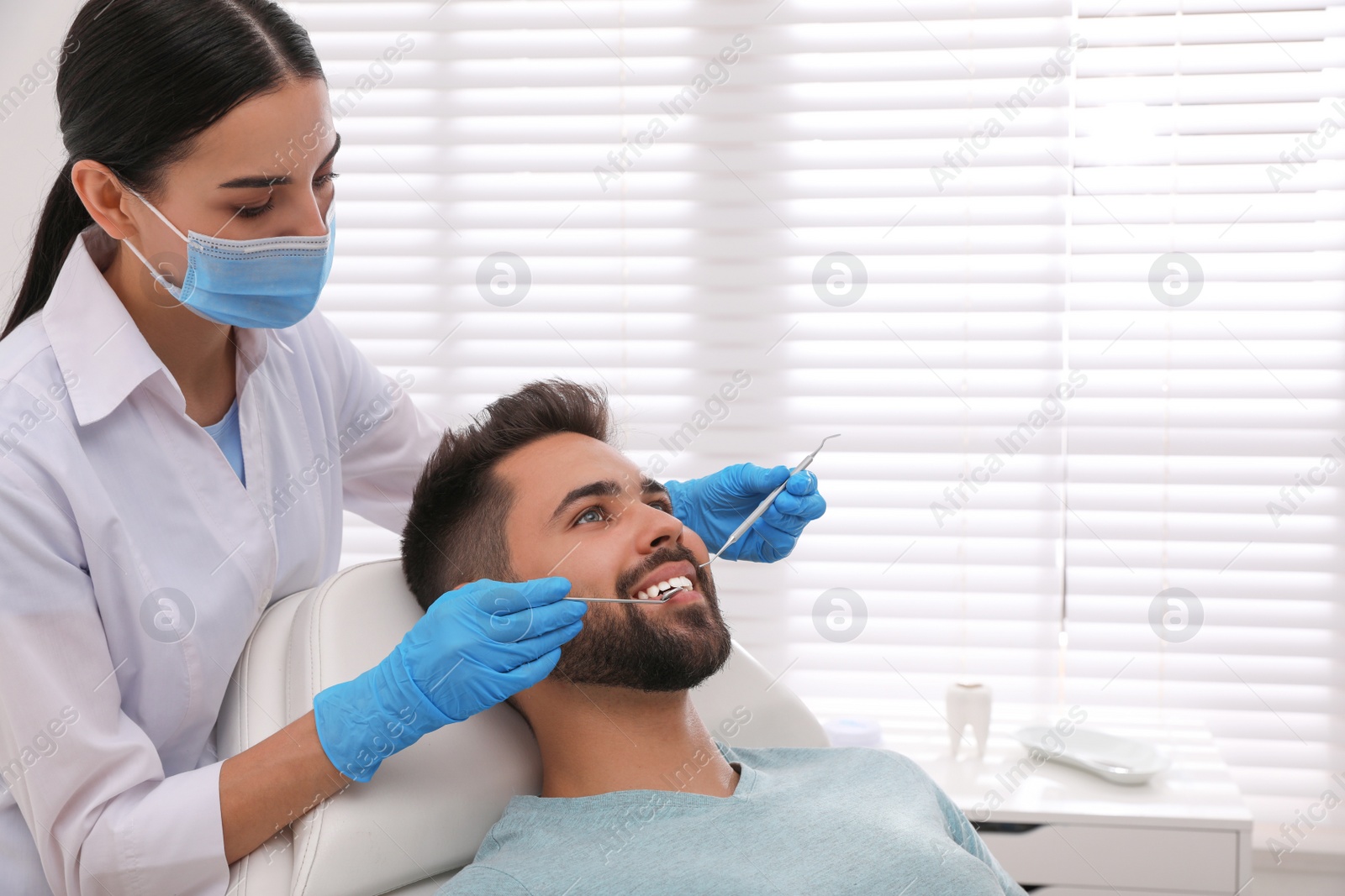 Photo of Dentist examining young man's teeth in modern clinic