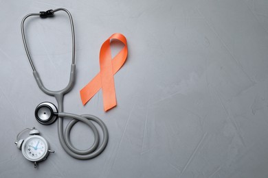 Orange ribbon, stethoscope and alarm clock on light grey table, flat lay with space for text. Multiple sclerosis awareness