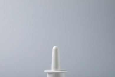 Photo of Bottle of nasal spray on grey background, closeup. Space for text