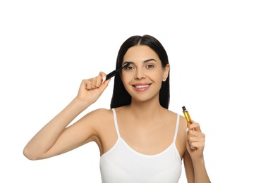 Photo of Young woman applying oil onto eyelashes on white background
