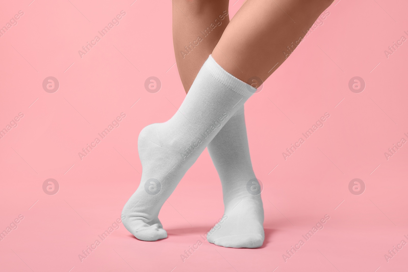 Photo of Woman in stylish white socks on pink background, closeup