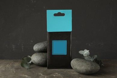 Photo of Scented sachet, spa stones and eucalyptus branches on grey table
