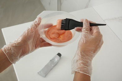 Photo of Woman preparing hair dye in bowl at home, closeup