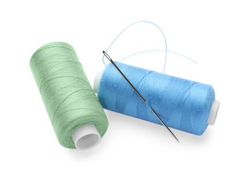 Different colorful sewing threads with needle on white background